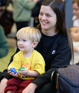 Child sitting on parent's lap and smiling during storytime.