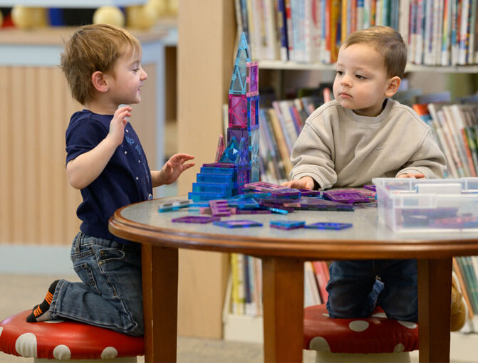 Two toddlers playing with blocks at a table