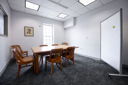 Small study room with a large table, chairs, and whiteboard.