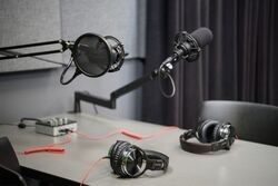 Podcast equipment including microphones and headphones set up at a table.