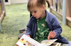 Child seated on floor reading a book