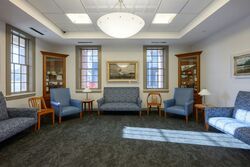 Brightly lit meeting room with chairs and couches along edges.