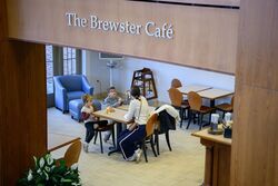 Family seated in cafe, sign overhead reads "Brewster Cafe"